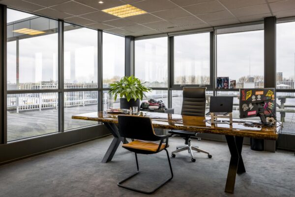 Modern kantoor aan de Anthony Fokkerweg met een houten bureau, grote ramen en uitzicht op een dakterras.